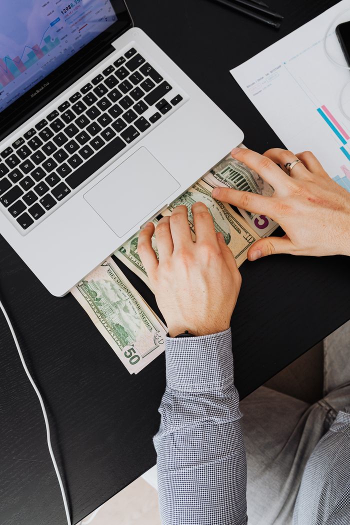 The Art of Drawing Readers In: Your attractive post title goes here Man counting US dollars at a laptop desk with chart papers, representing financial planning.