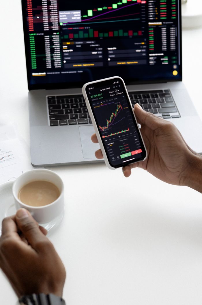 Contact Person analyzing stock market trends on smartphone with laptop background